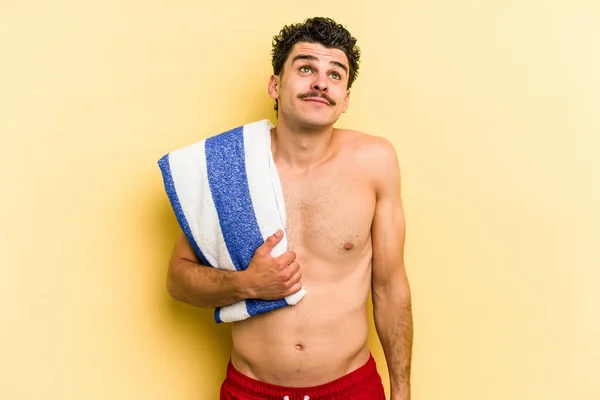 Young Caucasian Man Holding Beach Towel Isolated Yellow Background Dreaming — Photo