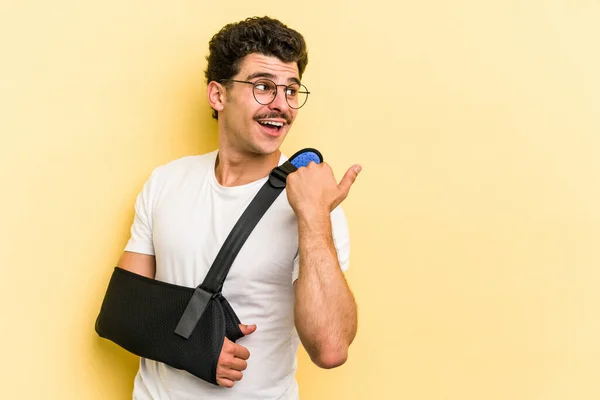 Young Caucasian Man Broke Hand Isolated Yellow Background Points Thumb — Fotografia de Stock