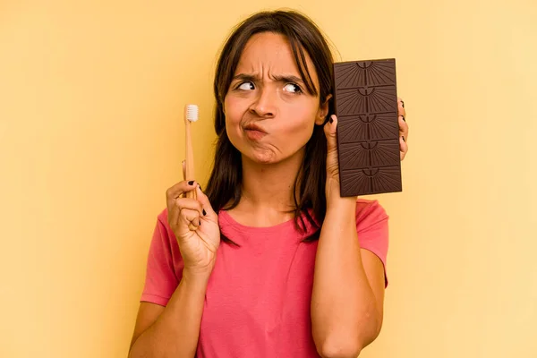 Young Hispanic Woman Washing Teeth Eating Chocolate Isolated Yellow Background — Foto de Stock