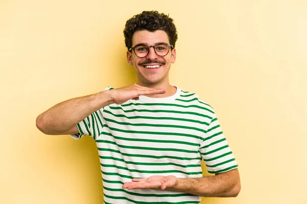 Young Caucasian Man Isolated Yellow Background Holding Something Both Hands — Stock Photo, Image
