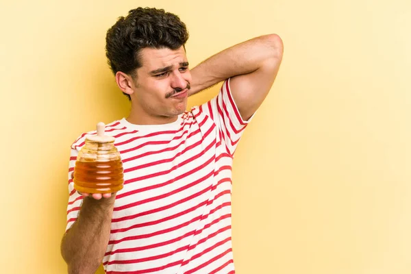 Young Caucasian Man Holding Honey Jar Isolated Yellow Background Touching — Stockfoto