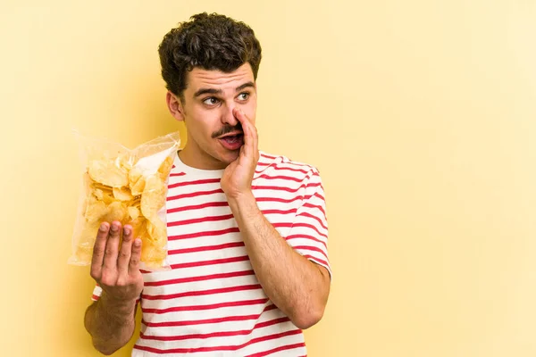 Young Caucasian Man Holding Bag Chips Isolated Yellow Background Saying — Stockfoto