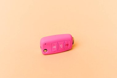 Pembe araba anahtarları bej arka planda izole edildi