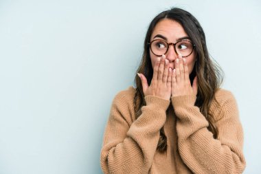 Kafkasyalı genç bir kadın mavi arka planda izole edilmiş düşünceli bir şekilde ağzıyla ağzını kapatan bir fotokopi odasına bakıyor..