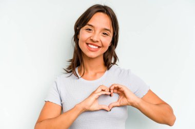 Mavi arka planda izole edilmiş genç İspanyol kadın bir göz kırptı ve elleriyle iyi bir jest yaptı..