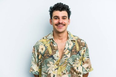 Mavi arka planda izole edilmiş genç beyaz adam mutlu, güler yüzlü ve neşeli.