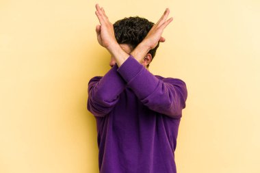 Sarı arka planda izole genç beyaz adam iki kolu çapraz tutuyor, inkar kavramı.