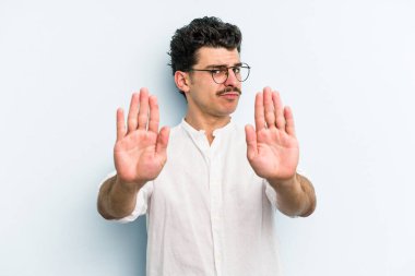 Mavi arka planda izole edilmiş genç beyaz adam elini uzatmış, dur işareti göstererek seni engelliyor..