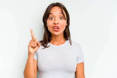 Latin kökenli genç bir kadın mavi arka planda izole edilmiş. Dedikodu yapıyor, bir şeyleri bildiriyor..