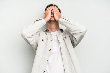 Beyaz arka planda izole olmuş genç beyaz bir adam ellerini başının üstünde tutarak neşeyle gülüyor. Mutluluk kavramı.