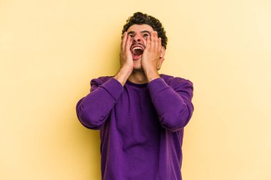 Kafkasyalı genç adam sarı arka planda izole edilmiş sızlanıyor ve ağlıyordu..