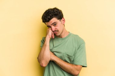 Sarı arka planda izole edilmiş genç beyaz adam tekrarlanan bir görevden bıktı..