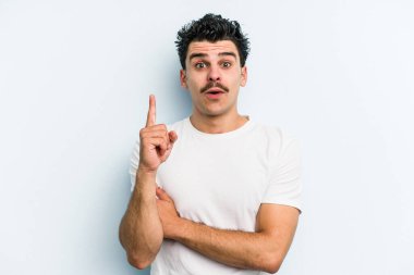 Kafkasyalı genç adam mavi arka planda izole edildi. Harika bir fikri var, yaratıcılık kavramı..