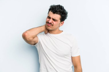 Kafkasyalı genç adam mavi arka planda izole edilmiş. Stres yüzünden boynu ağrıyor. Masaj yapıyor ve elle dokunuyor..