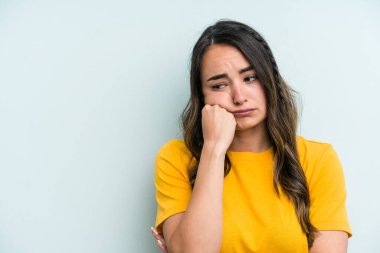 Mavi arka planda izole edilmiş, üzgün ve dalgın hisseden, kopyalama alanına bakan beyaz bir kadın..