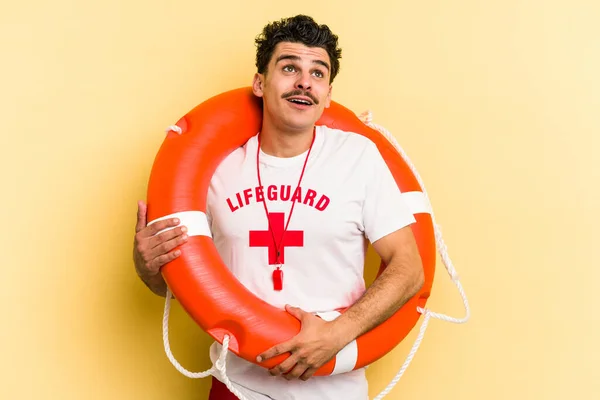 Young caucasian lifeguard man isolated on yellow background dreaming of achieving goals and purposes