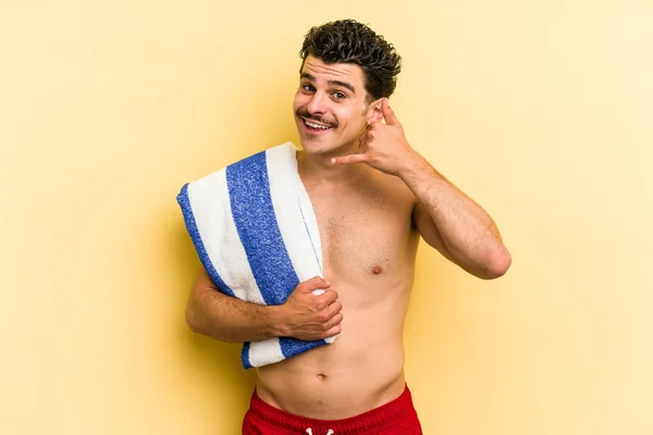 Young Caucasian Man Holding Beach Towel Isolated Yellow Background Showing — Photo