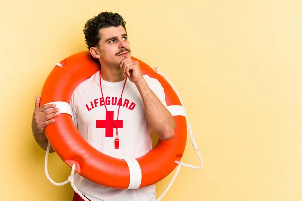 Young Caucasian Lifeguard Man Isolated Yellow Background Looking Sideways Doubtful — ストック写真