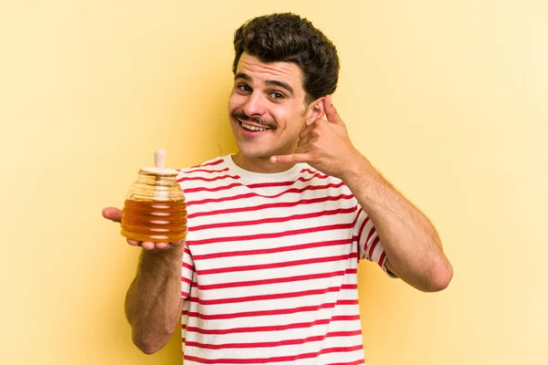 Young Caucasian Man Holding Honey Jar Isolated Yellow Background Showing – stockfoto
