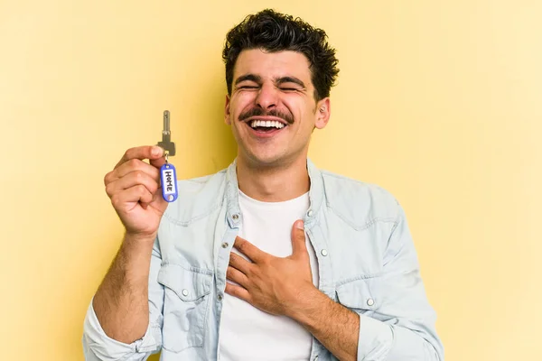 Young Caucasian Man Holding Home Keys Isolated Yellow Background Laughs — Stockfoto