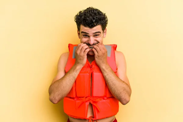 Young Caucasian Man Wearing Life Jacket Isolated Yellow Background Biting — 图库照片