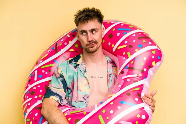 Young Caucasian Man Holding Inflatable Donut Isolated Yellow Background Confused — 图库照片