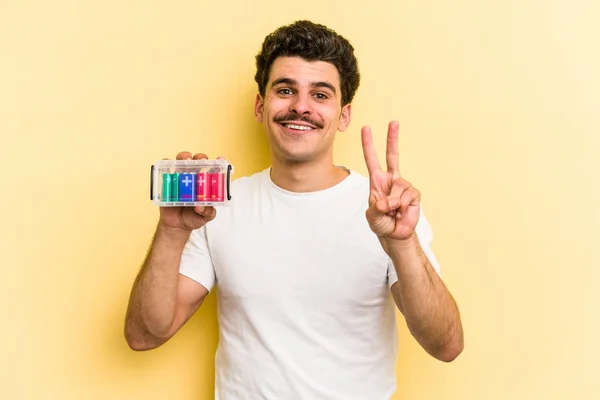 Young Caucasian Man Holding Batteries Isolated Yellow Background Showing Number — Foto Stock