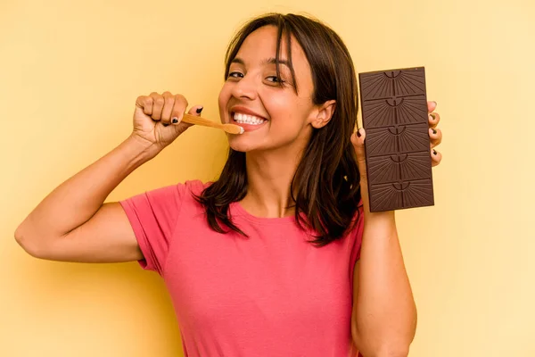 Young Hispanic Woman Washing Teeth Eating Chocolate Isolated Yellow Background — Stockfoto