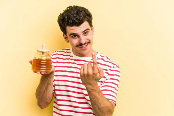 Young Caucasian Man Holding Honey Jar Isolated Yellow Background Pointing — Stockfoto