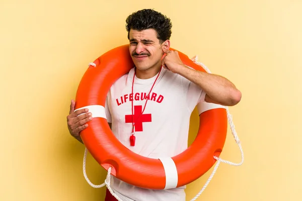 Young caucasian lifeguard man isolated on yellow background covering ears with hands.