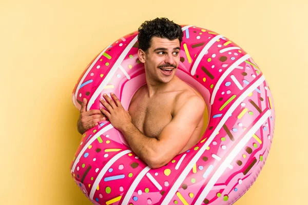 Young Caucasian Man Holding Inflatable Donut Isolated Yellow Background Looks — 图库照片