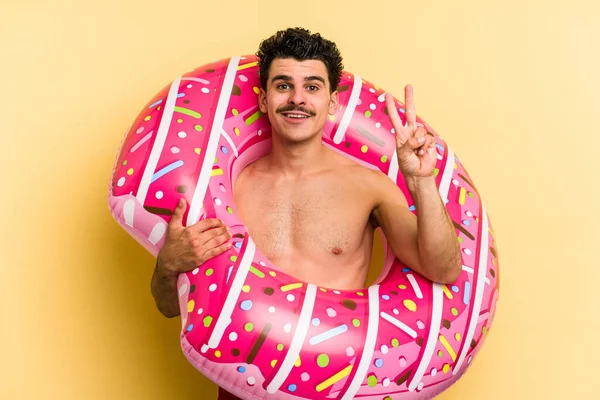 Young Caucasian Man Holding Inflatable Donut Isolated Yellow Background Showing — Stock fotografie