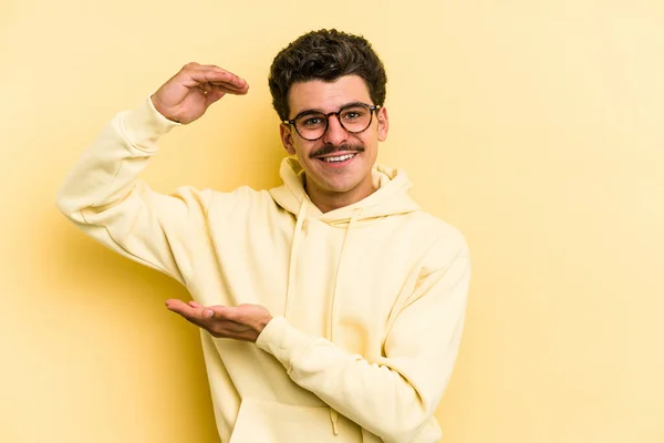 Young Caucasian Man Isolated Yellow Background Holding Something Little Forefingers — Stock Photo, Image