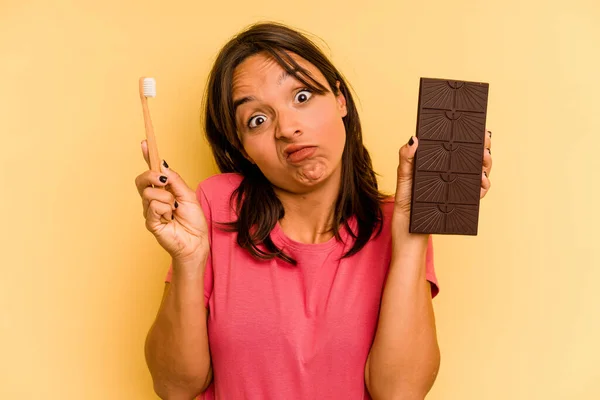 Young Hispanic Woman Washing Teeth Eating Chocolate Isolated Yellow Background — Stock fotografie