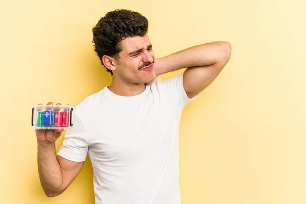 Young Caucasian Man Holding Batteries Isolated Yellow Background Touching Back — 图库照片