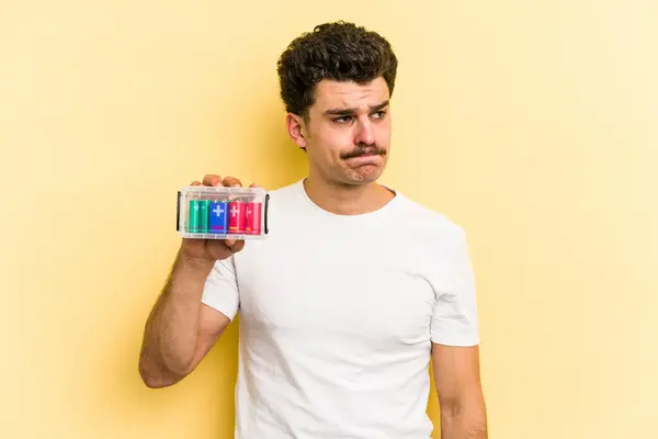 Young Caucasian Man Holding Batteries Isolated Yellow Background Confused Feels — Foto Stock