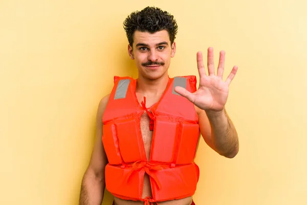 Young Caucasian Man Wearing Life Jacket Isolated Yellow Background Smiling — Stok fotoğraf