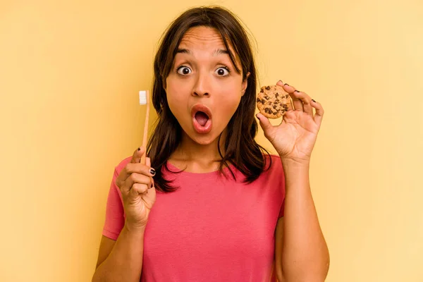 Young Hispanic Woman Washing Teeth Eating Cookies Isolated Yellow Background — Stok fotoğraf