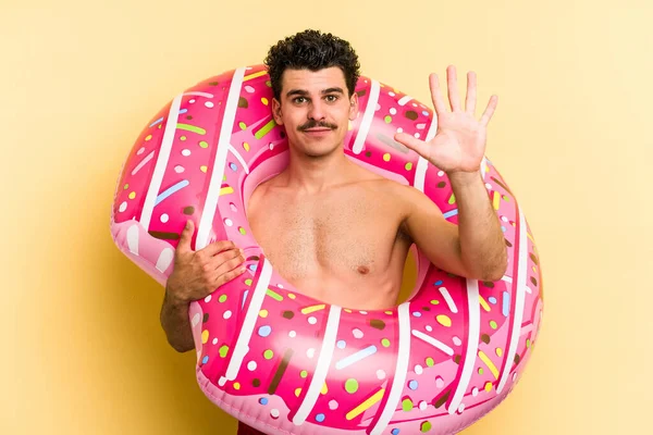 Young Caucasian Man Holding Inflatable Donut Isolated Yellow Background Smiling — 图库照片