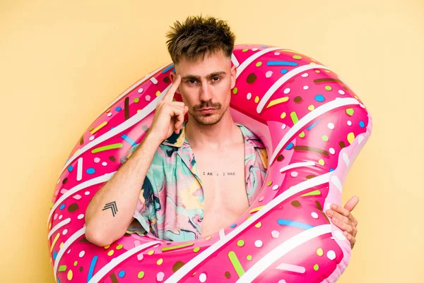 Young Caucasian Man Holding Inflatable Donut Isolated Yellow Background Pointing — 图库照片