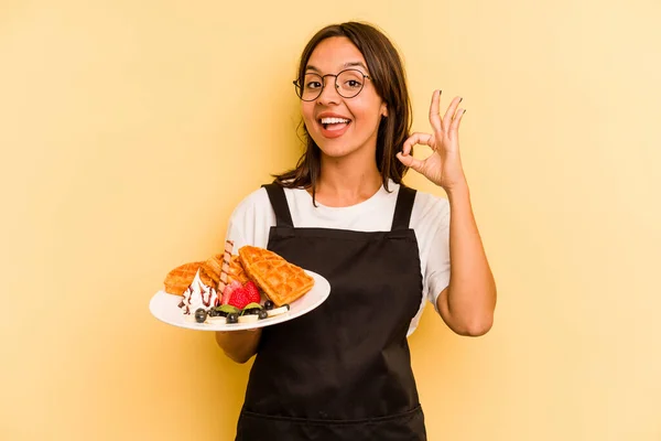 Young Hispanic Dependent Woman Holding Waffles Isolated Yellow Background Cheerful — Stock Photo, Image