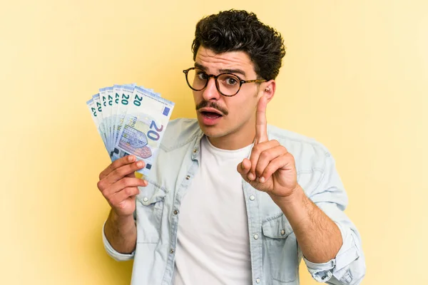 Young Caucasian Man Holding Banknotes Isolated Yellow Background Having Idea — Foto de Stock
