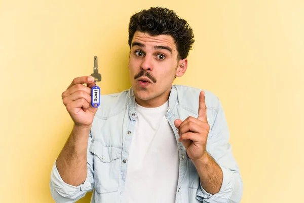 Young Caucasian Man Holding Home Keys Isolated Yellow Background Having — Stock Fotó