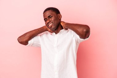 Genç Afro-Amerikan erkek, pembe arka planda izole edilmiş, sabit yaşam tarzından dolayı boyun ağrısı çekiyor..