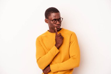 Beyaz arka planda izole edilmiş genç Afrikalı Amerikalı şüpheli ve şüpheci bir ifadeyle yana bakıyor..