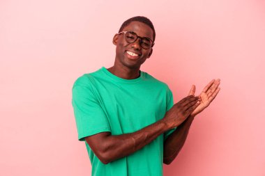 Genç Afro-Amerikan erkeği pembe arka planda izole edilmiş enerjik ve rahat hissediyor, kendinden emin ellerini ovuşturuyor..