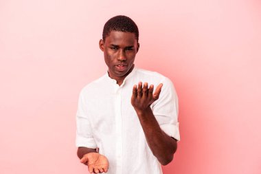 Pembe arka planda izole edilmiş genç Afrikalı Amerikalı adam kollarıyla ölçek oluşturuyor, mutlu ve kendinden emin hissediyor..