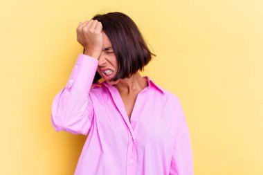 Sarı arka planda izole edilmiş genç bir ırk kadını bir şeyi unutuyor, alnına avuç içi ile vuruyor ve gözlerini kapatıyor..