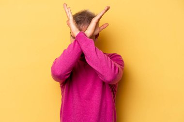 Sarı arka planda izole genç beyaz adam iki kolu çapraz tutuyor, inkar kavramı.