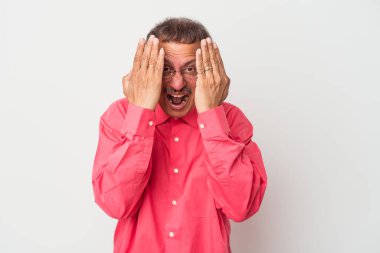 Middle aged indian man isolated on white background having fun covering half of face with palm.
